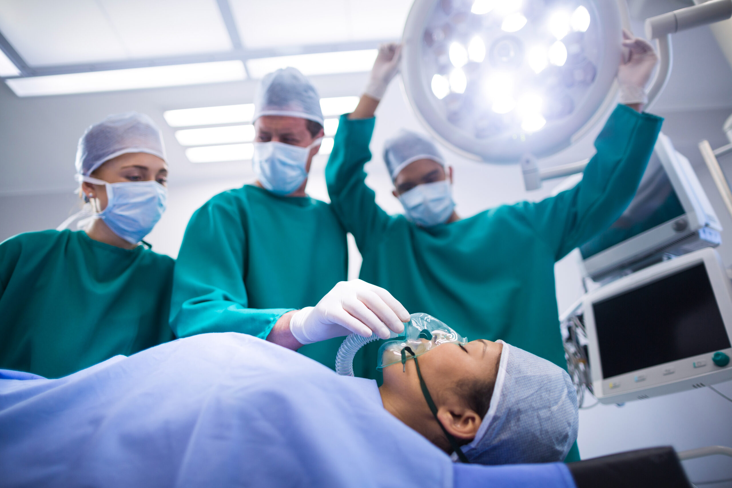 Surgeons adjusting oxygen mask on patient mouth in operation theater of hospital